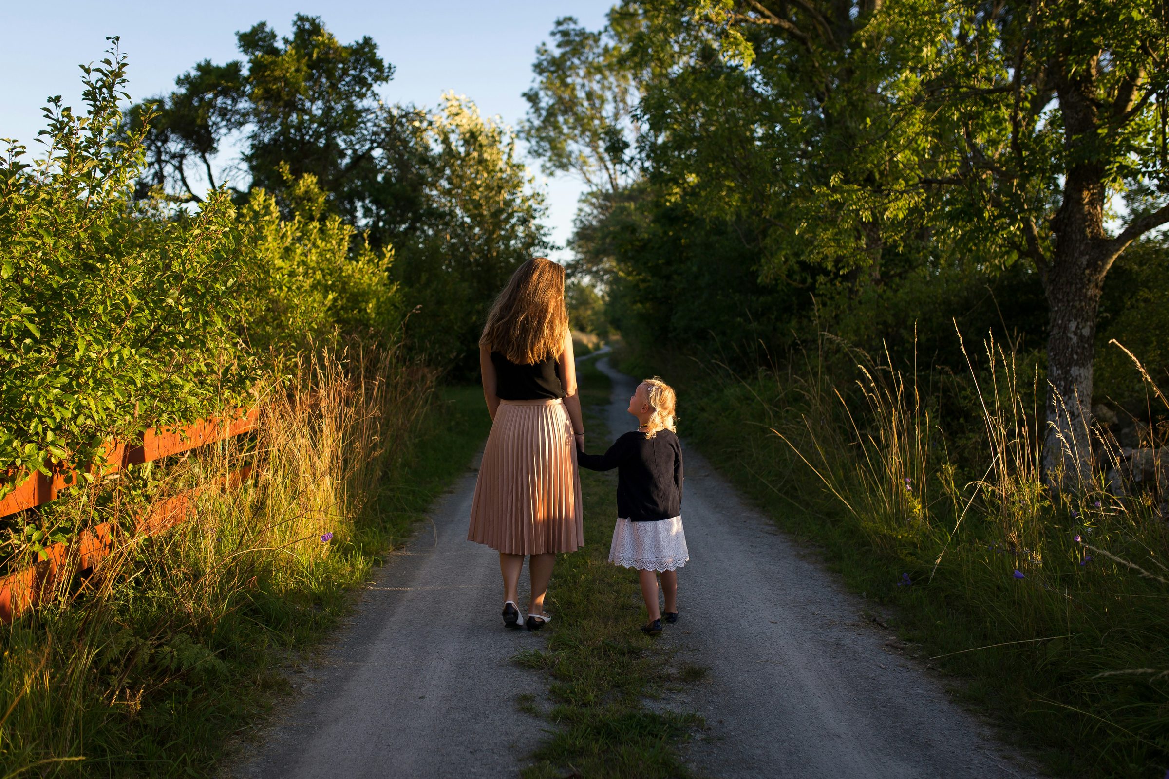 A mother and daughter walking hand in hand down a country road
